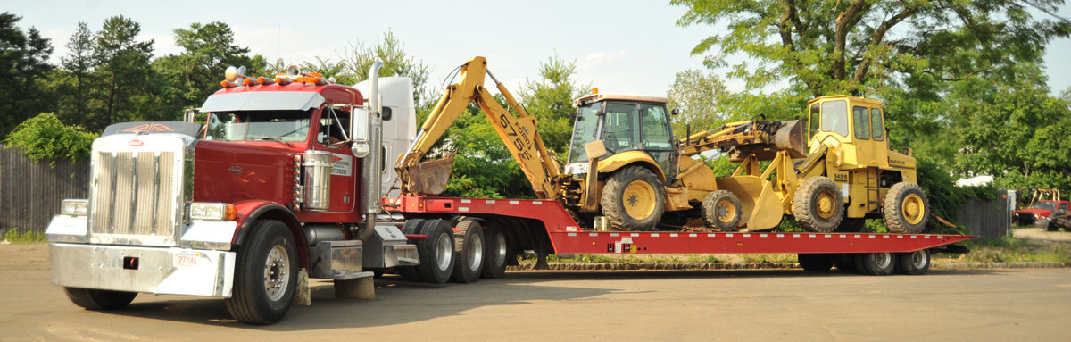 TowXperts red Peterbilt heavy duty truck hauling construction equipment on a lowboy trailer